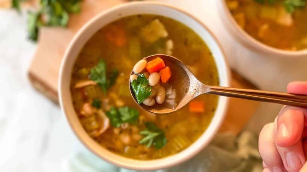 A person holding a spoon full of soup.