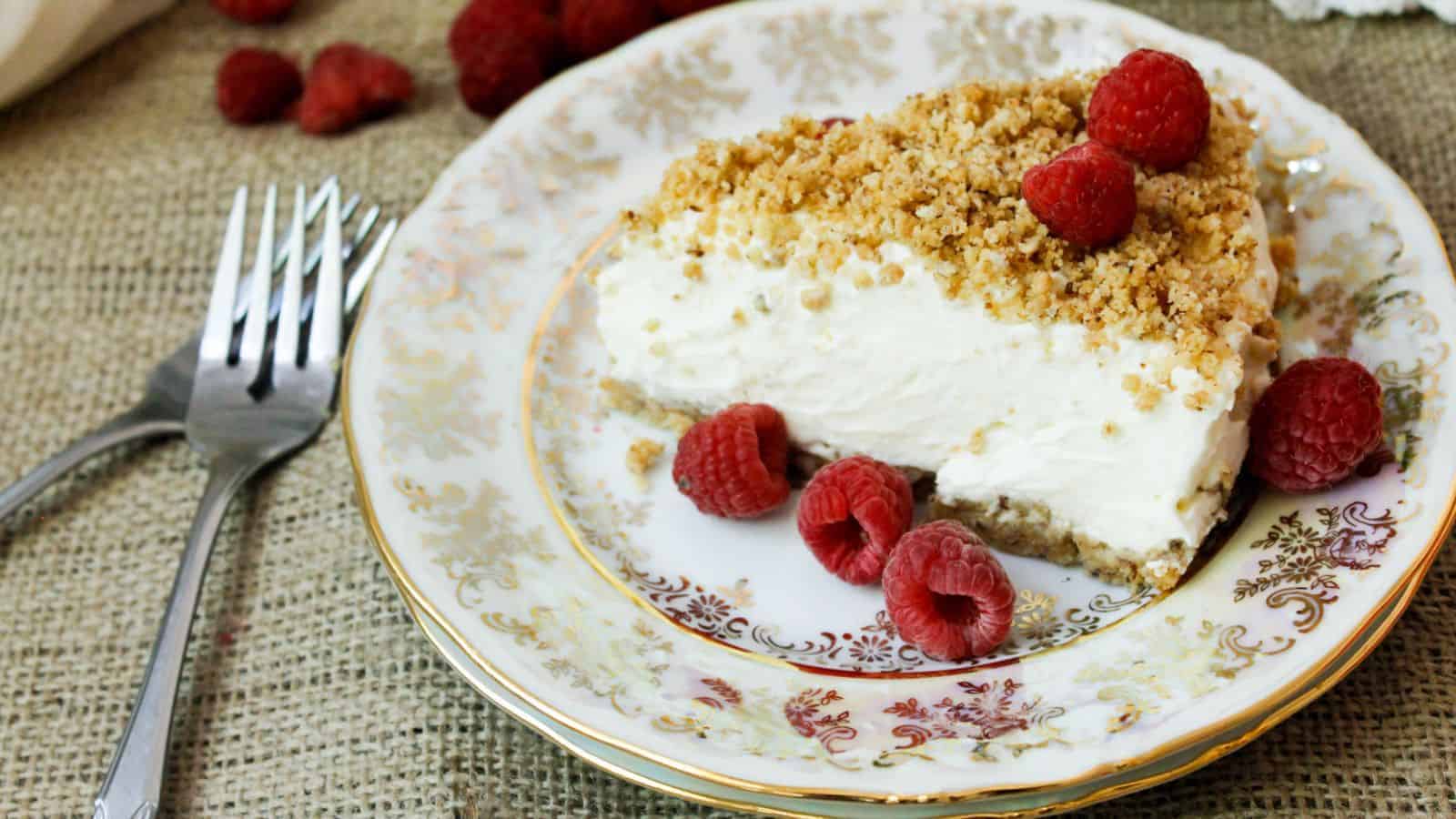 A slice of cheesecake with raspberries on a plate.