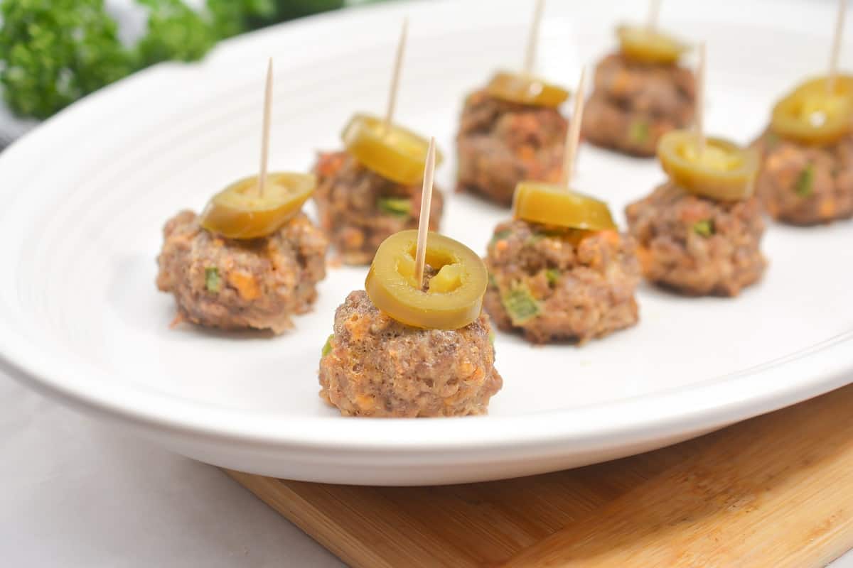 Meatballs on toothpicks on a white plate.