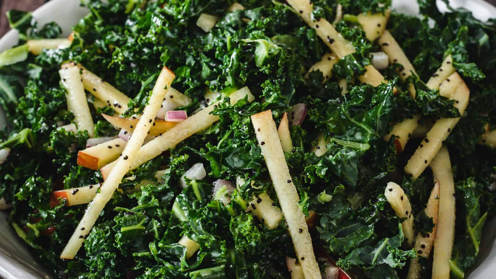 A bowl of kale salad on a wooden table.