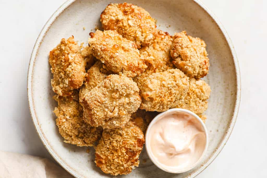 Chicken nuggets on a plate with dipping sauce.