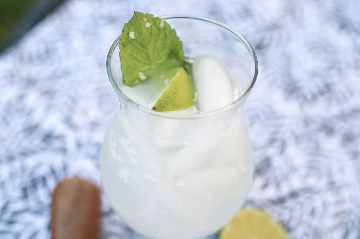 A glass of mojito with ice and lime on a table.