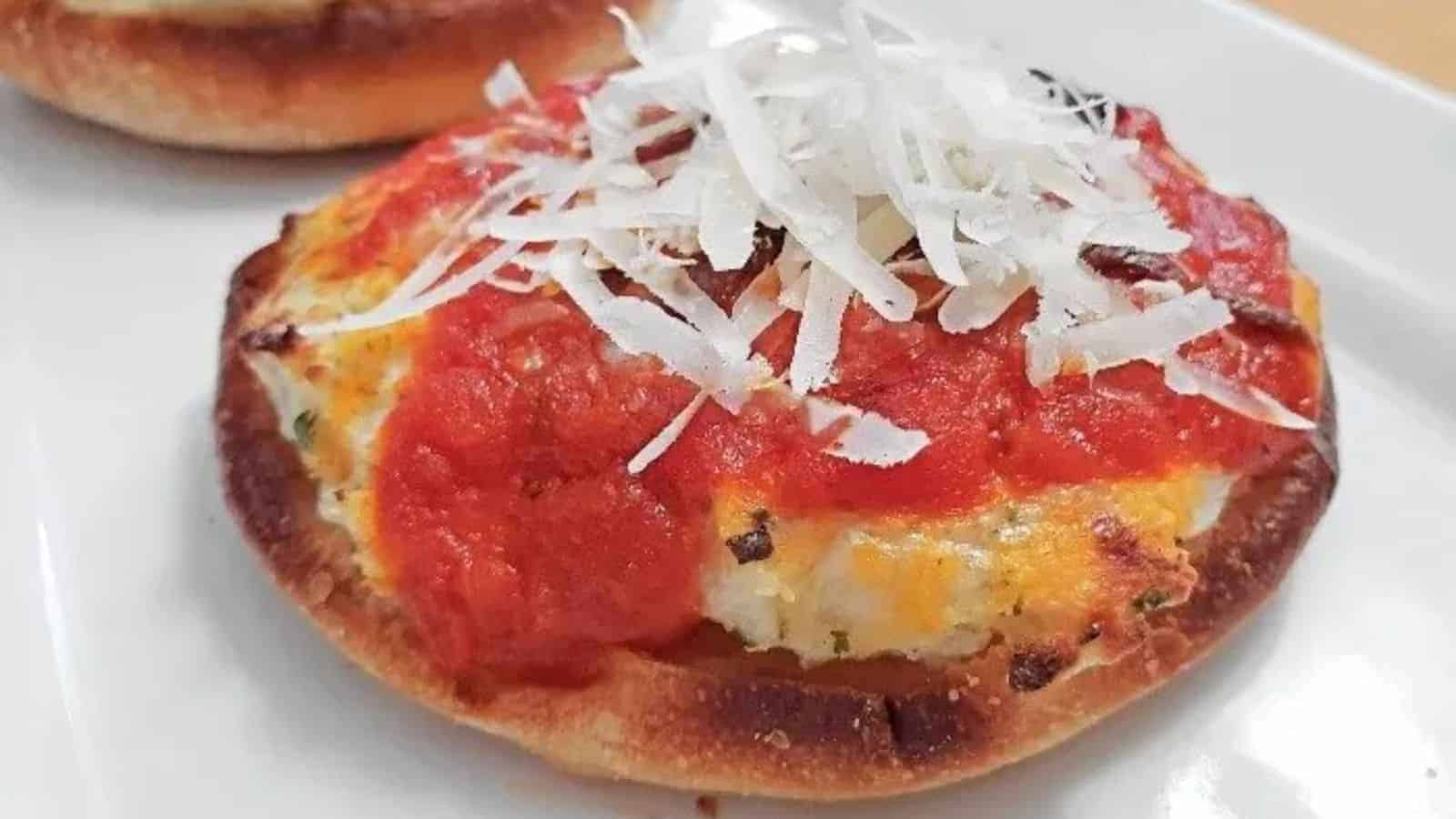 Image shows a close up of a Lasagna Pizza Appetizer topped with freshly grated parmesan sitting on a white plate with another one in the background.