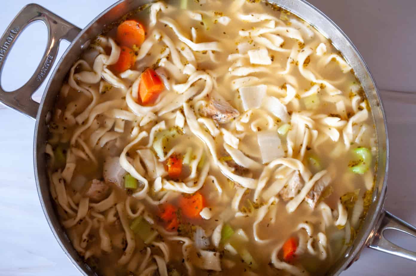 A ladle full of turkey noodle soup.