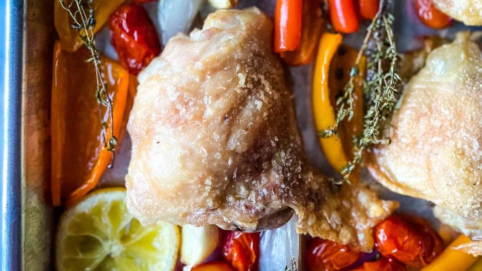 Chicken legs in a baking pan with lemons and herbs.