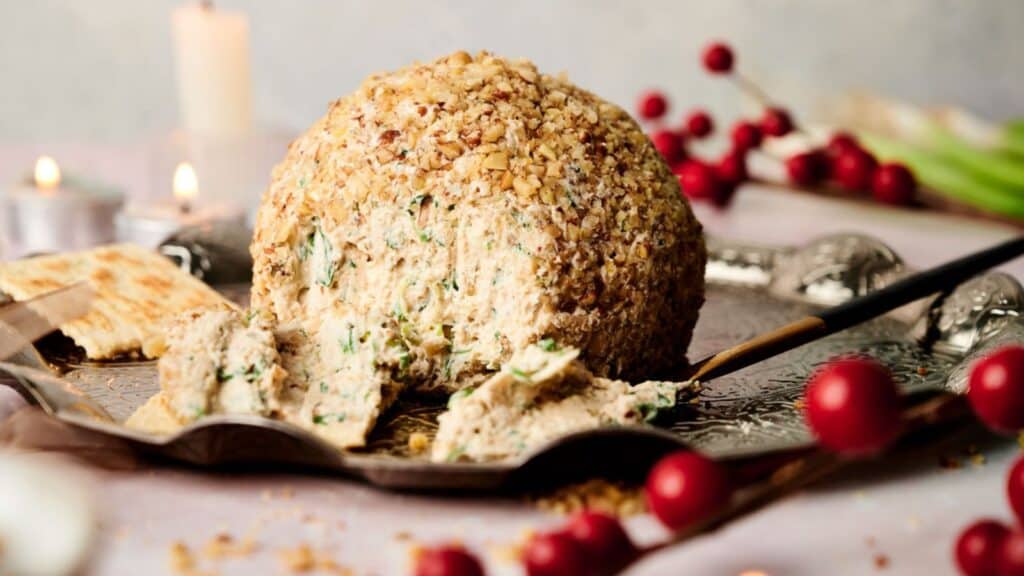 A cheese ball on a silver plate with crackers.