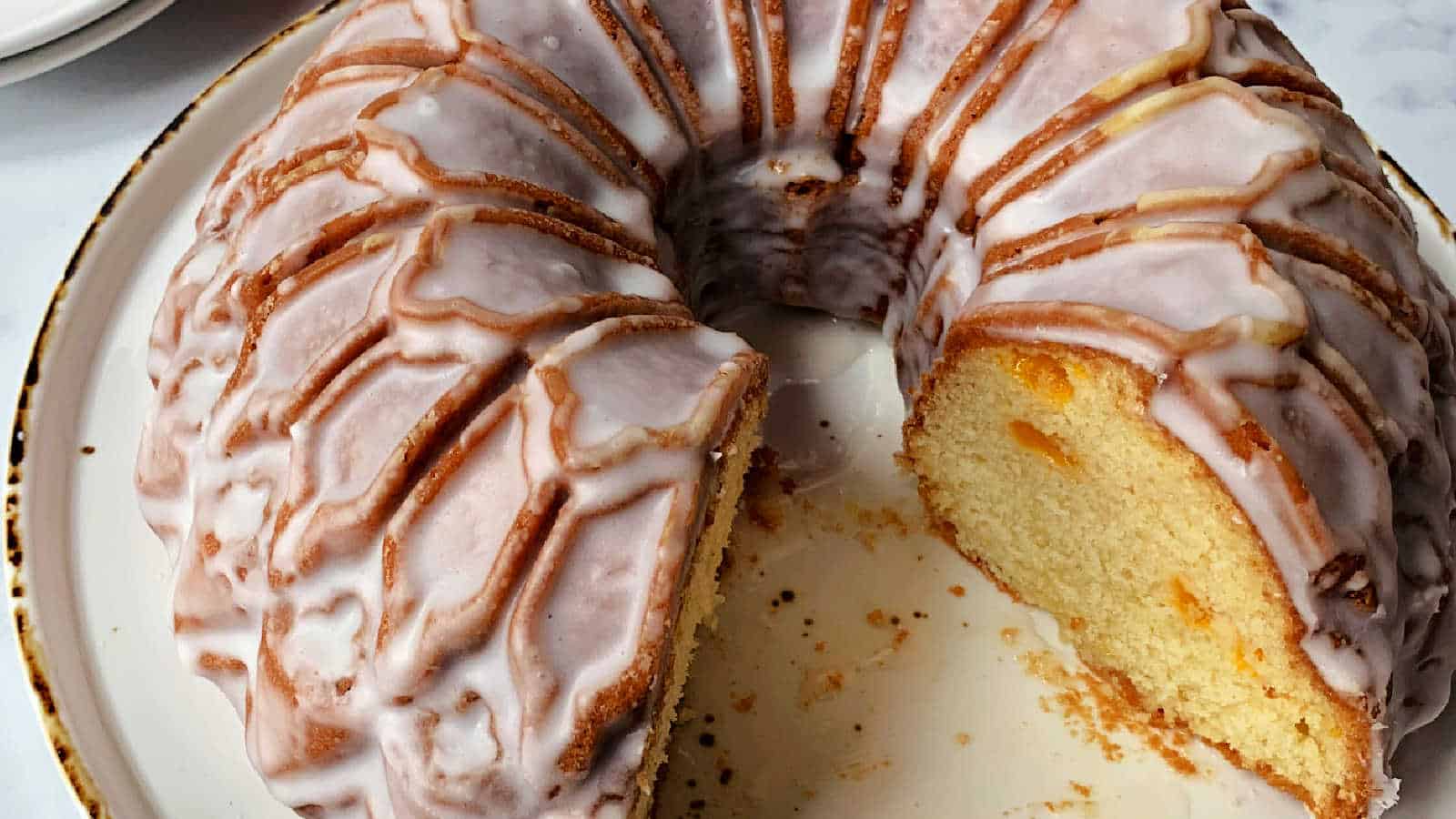 A sliced mandarin orange bundt cake on a white plate.