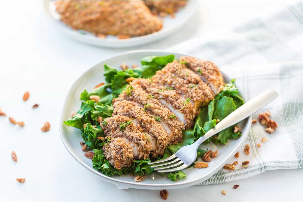 A plate with chicken breasts and greens on it.