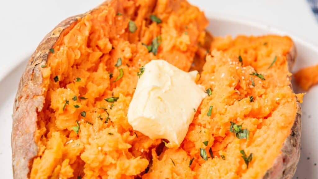 A baked sweet potato with butter on a plate.