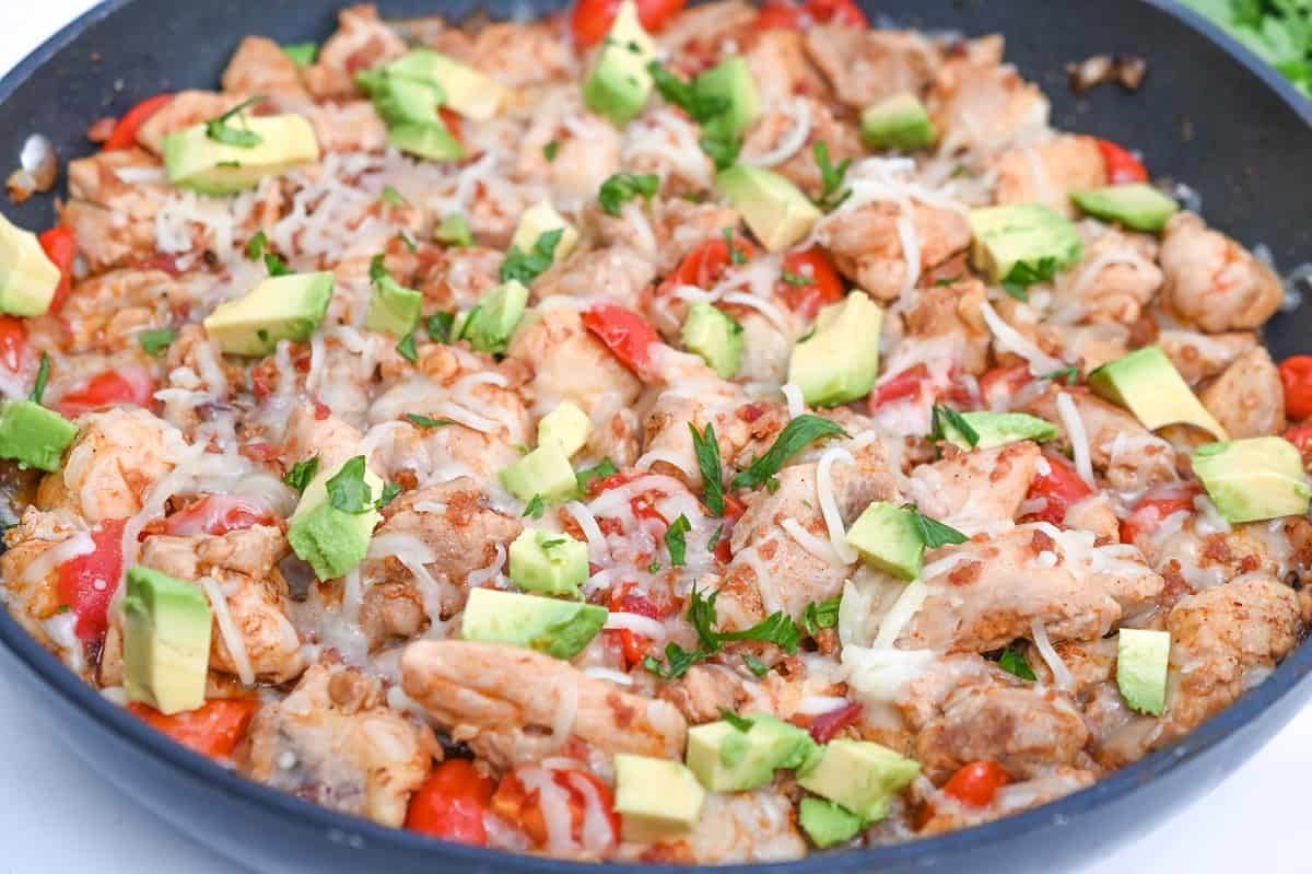 Chicken fajitas in a skillet with avocado.