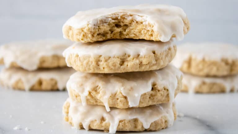 A stack of cookies with icing and a bite taken out.