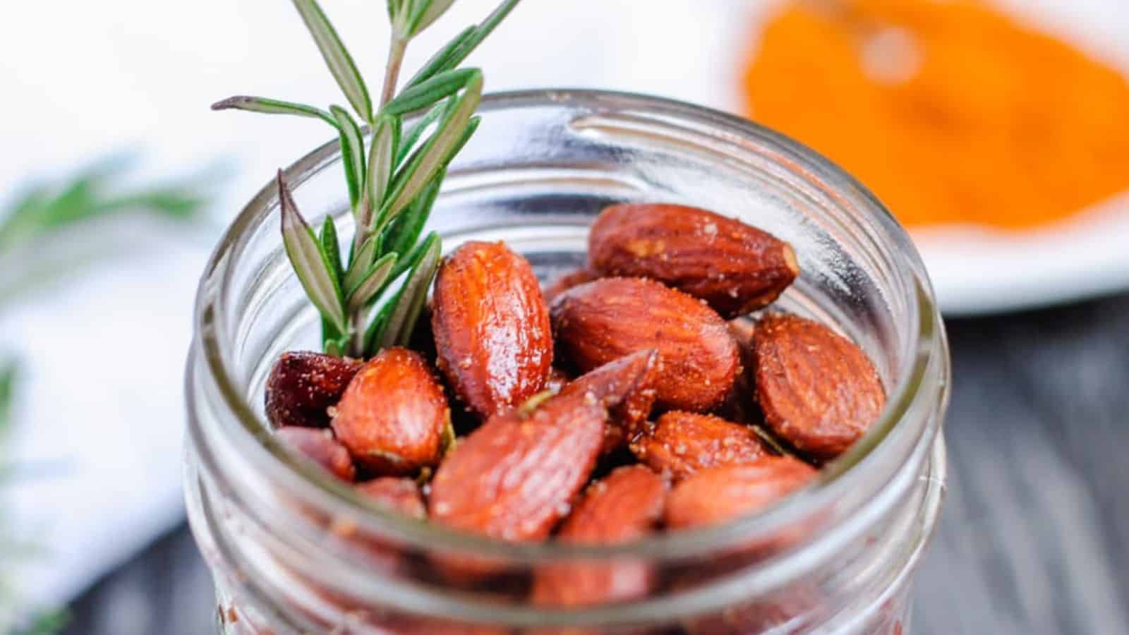 Almonds in a jar with rosemary and spices.