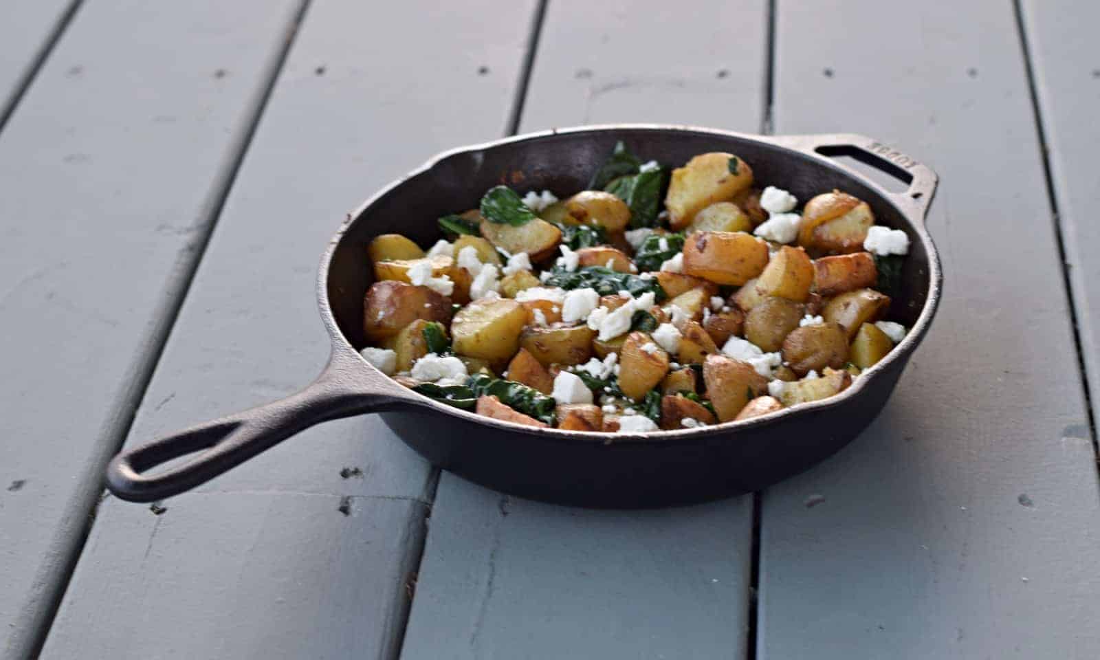 A skillet filled with potatoes and feta cheese.