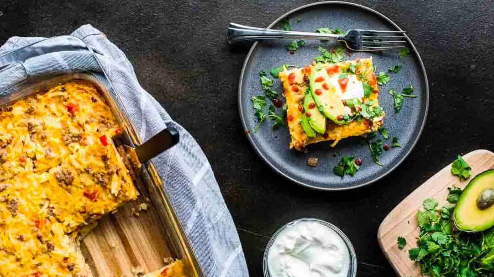 An overhead shot of breakfast casserole next to a single serving and a toppings bar.