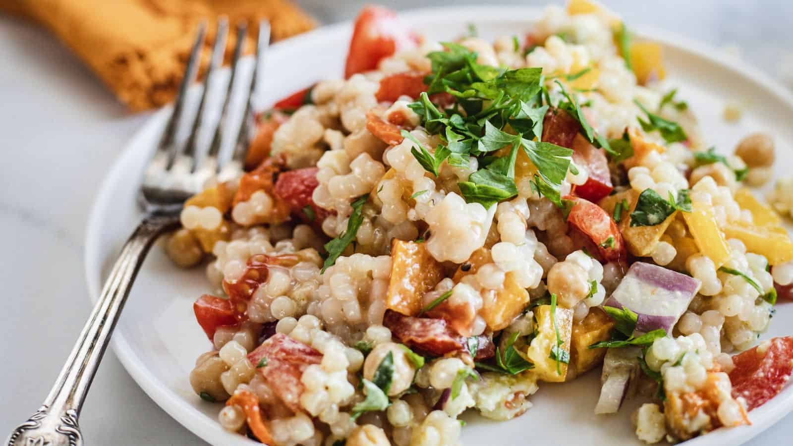 A plate of couscous salad with tomatoes and parsley, perfect for holiday appetizers.