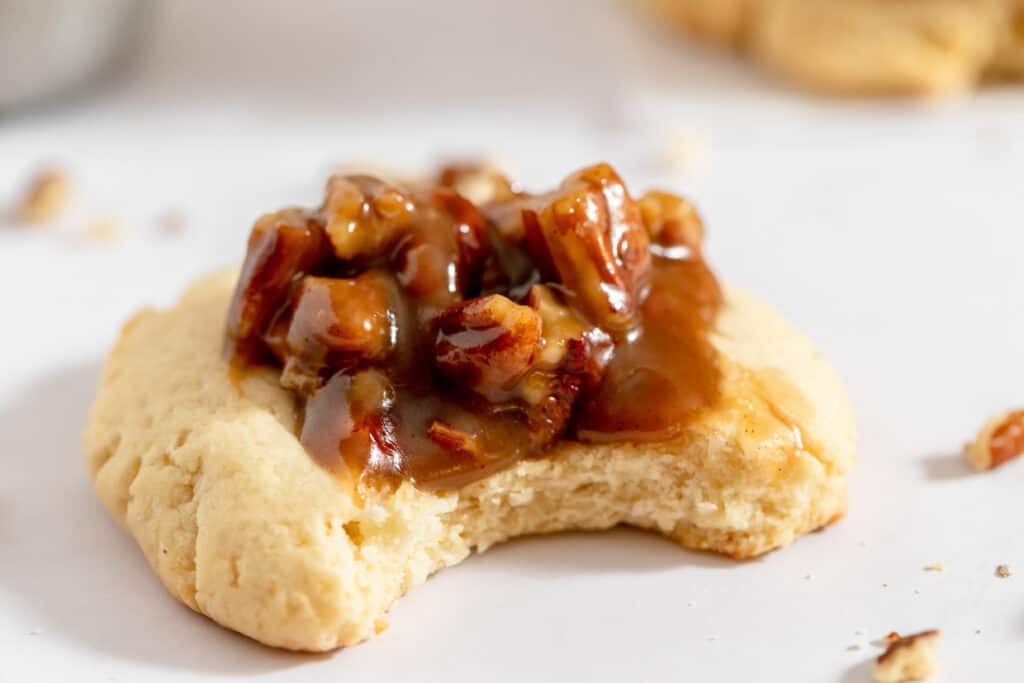 A cookie with caramel and pecans on top.