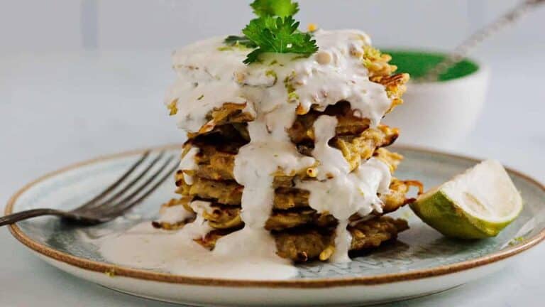 A stack of pancakes on a plate with a lime wedge.