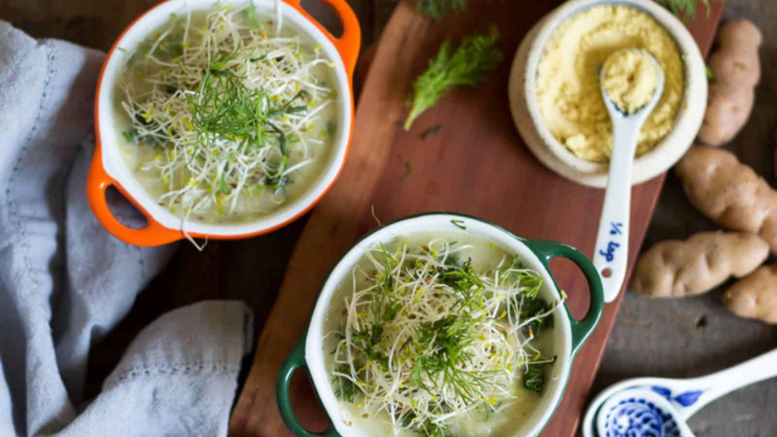 Two bowls of soup on a wooden cutting board.