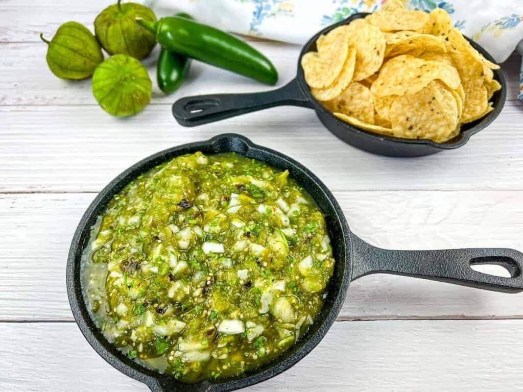 Roasted tomatillo salsa in a skillet with chips and tortillas.