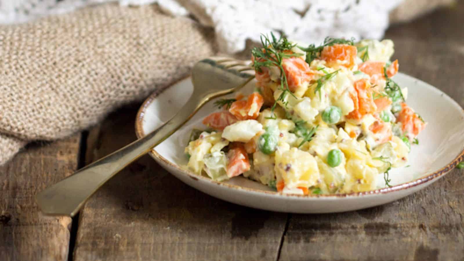 A bowl of carrot and potato salad on a wooden table.