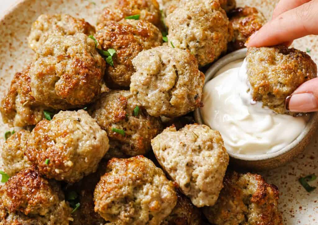 Sausage balls on a plate with a dipping sauce.