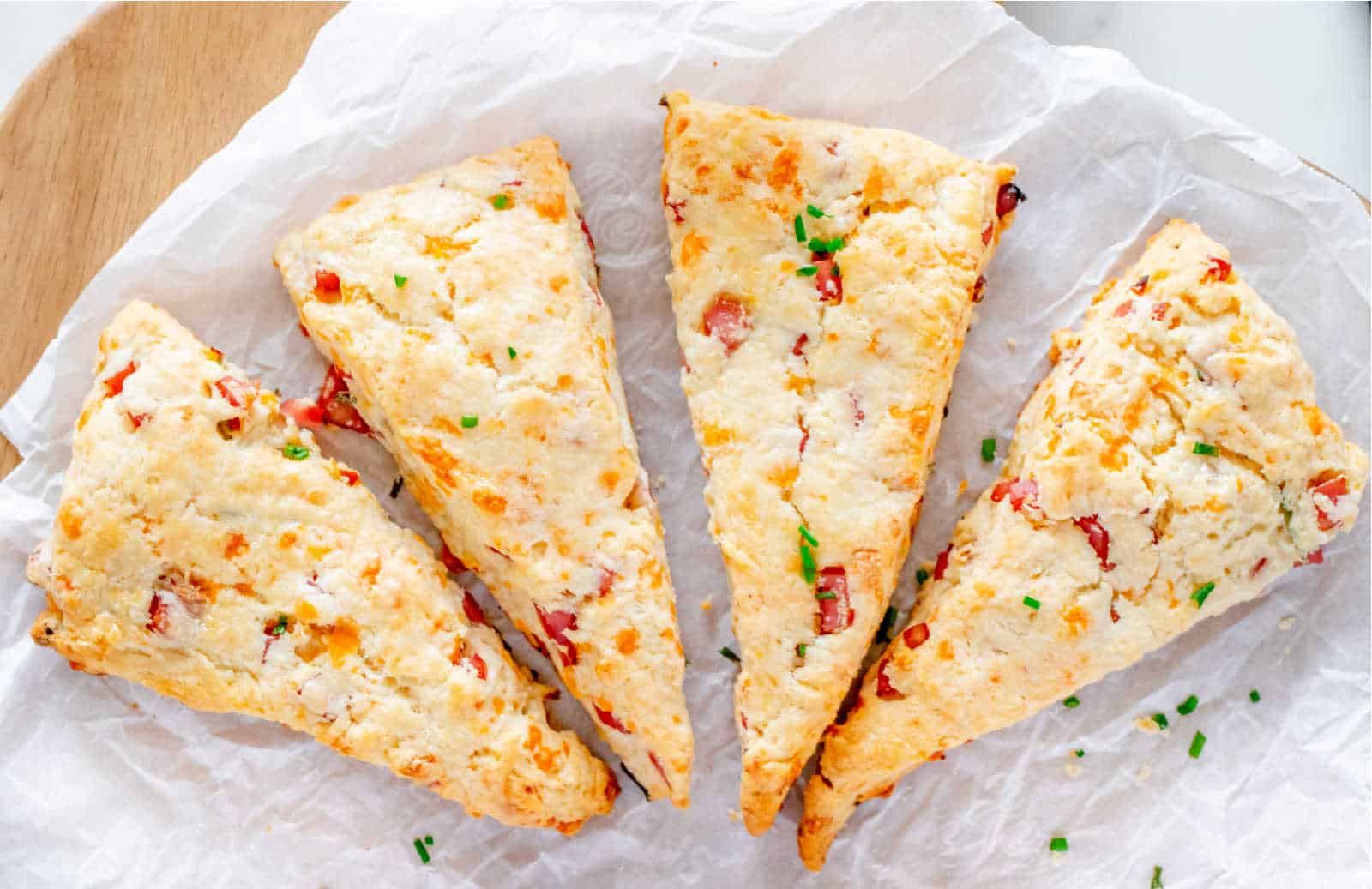 Four ham and cheese scones on a piece of white paper.