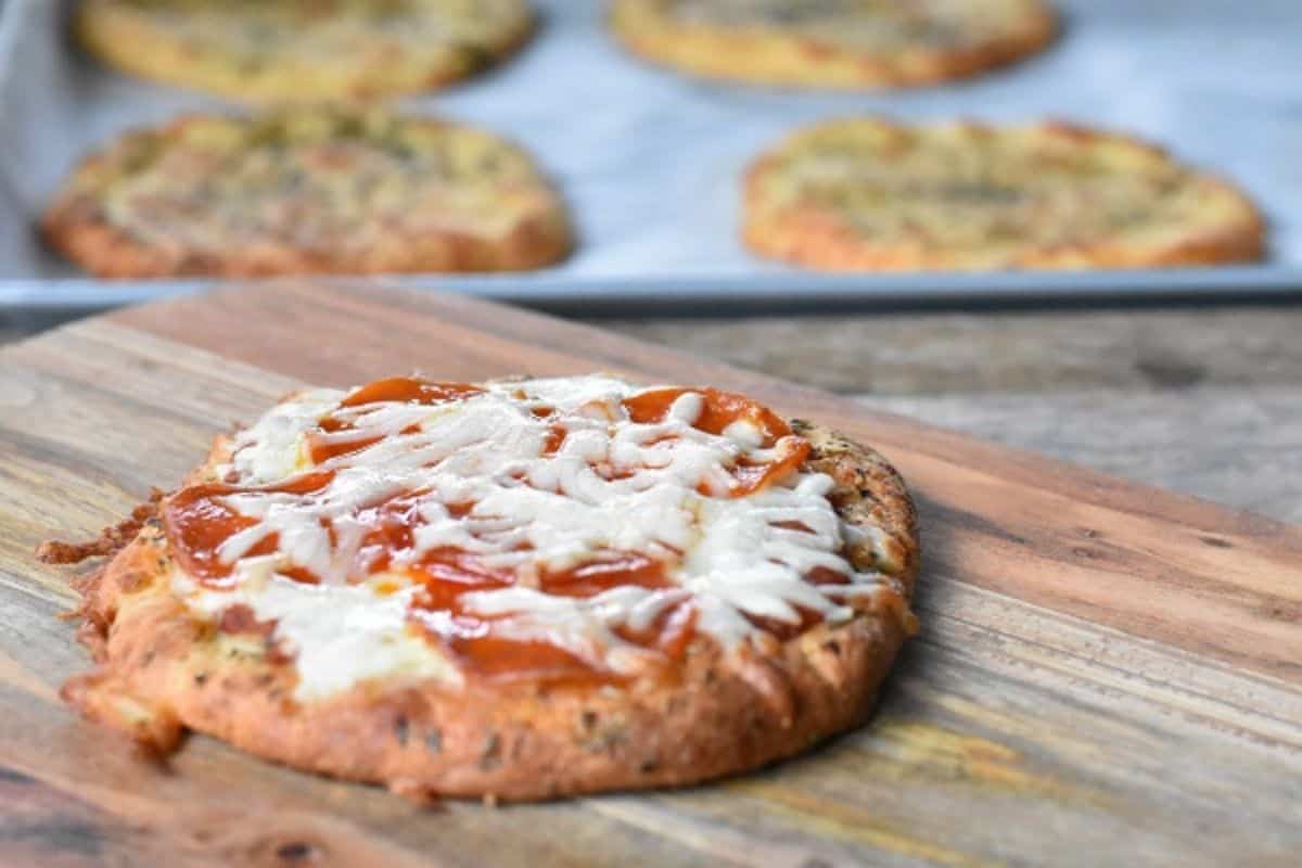 A pizza on a wooden cutting board.