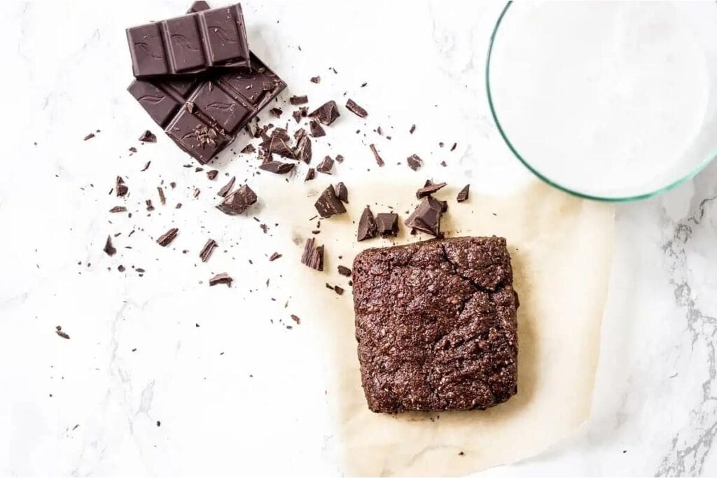 A brownie with chocolate chips and a glass of milk.