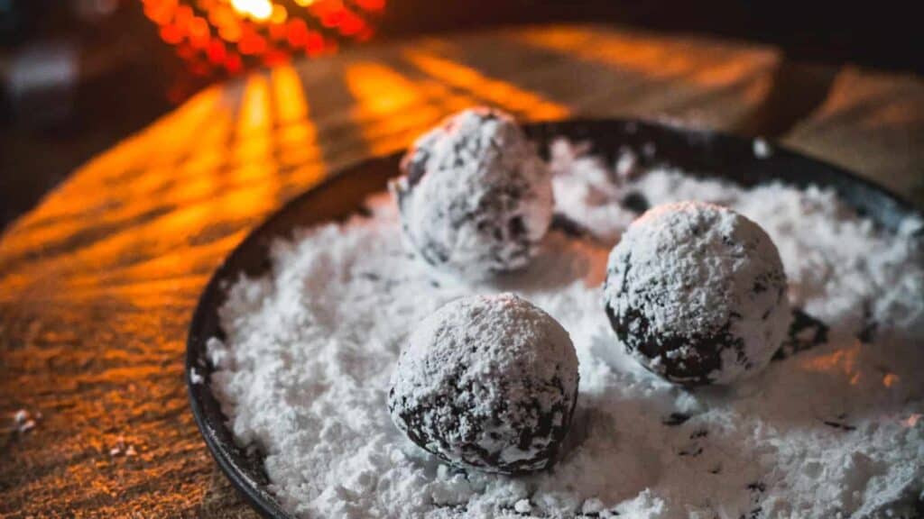 Chocolate truffles with powdered sugar on a plate.