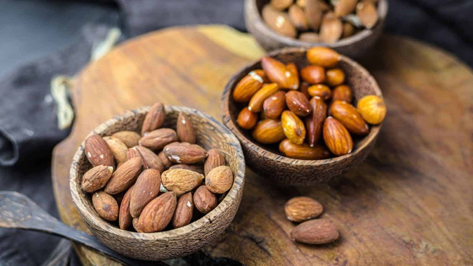 Almonds in bowls on a wooden cutting board.