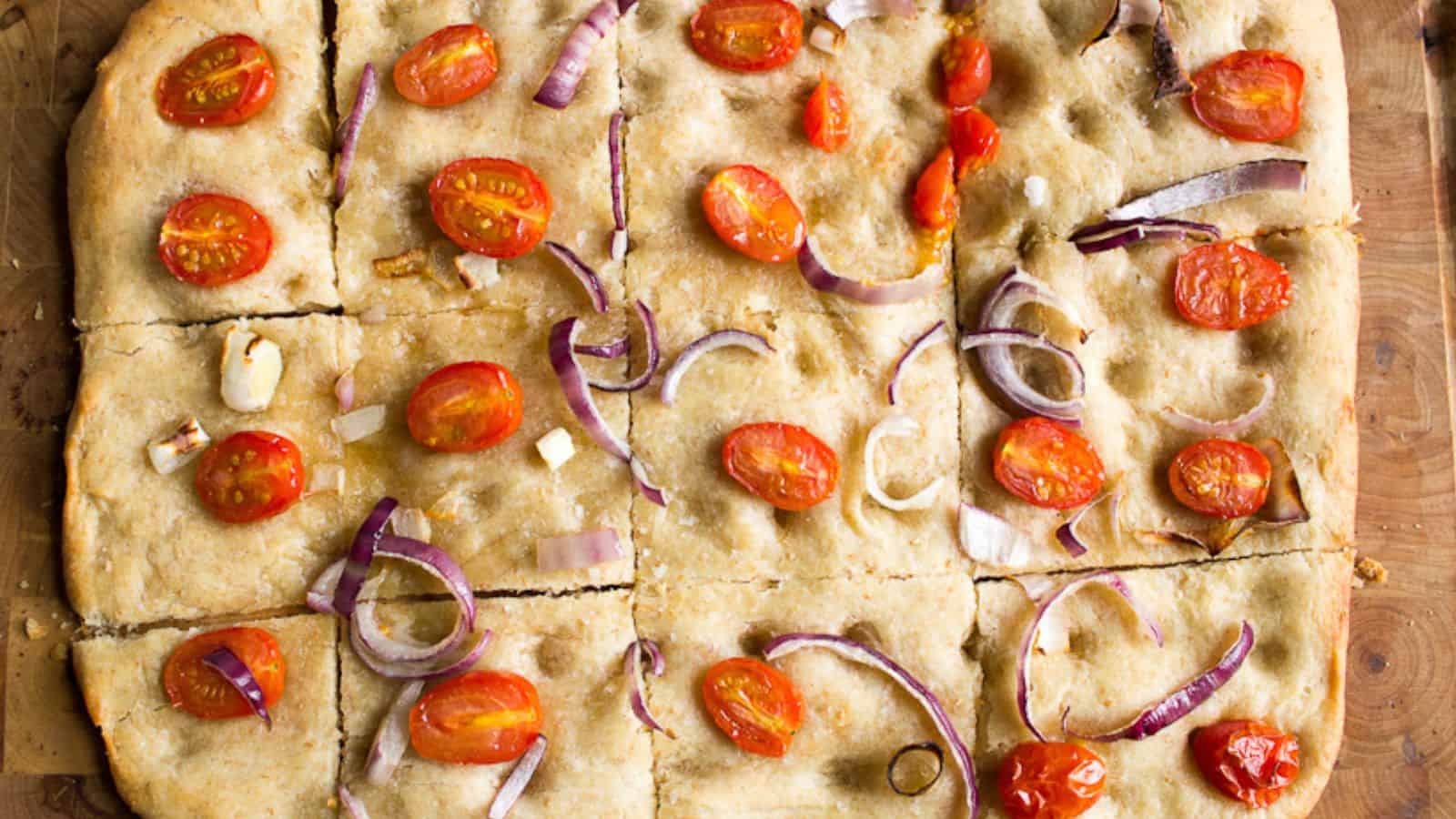 Focaccia on a cutting board sliced into squares.