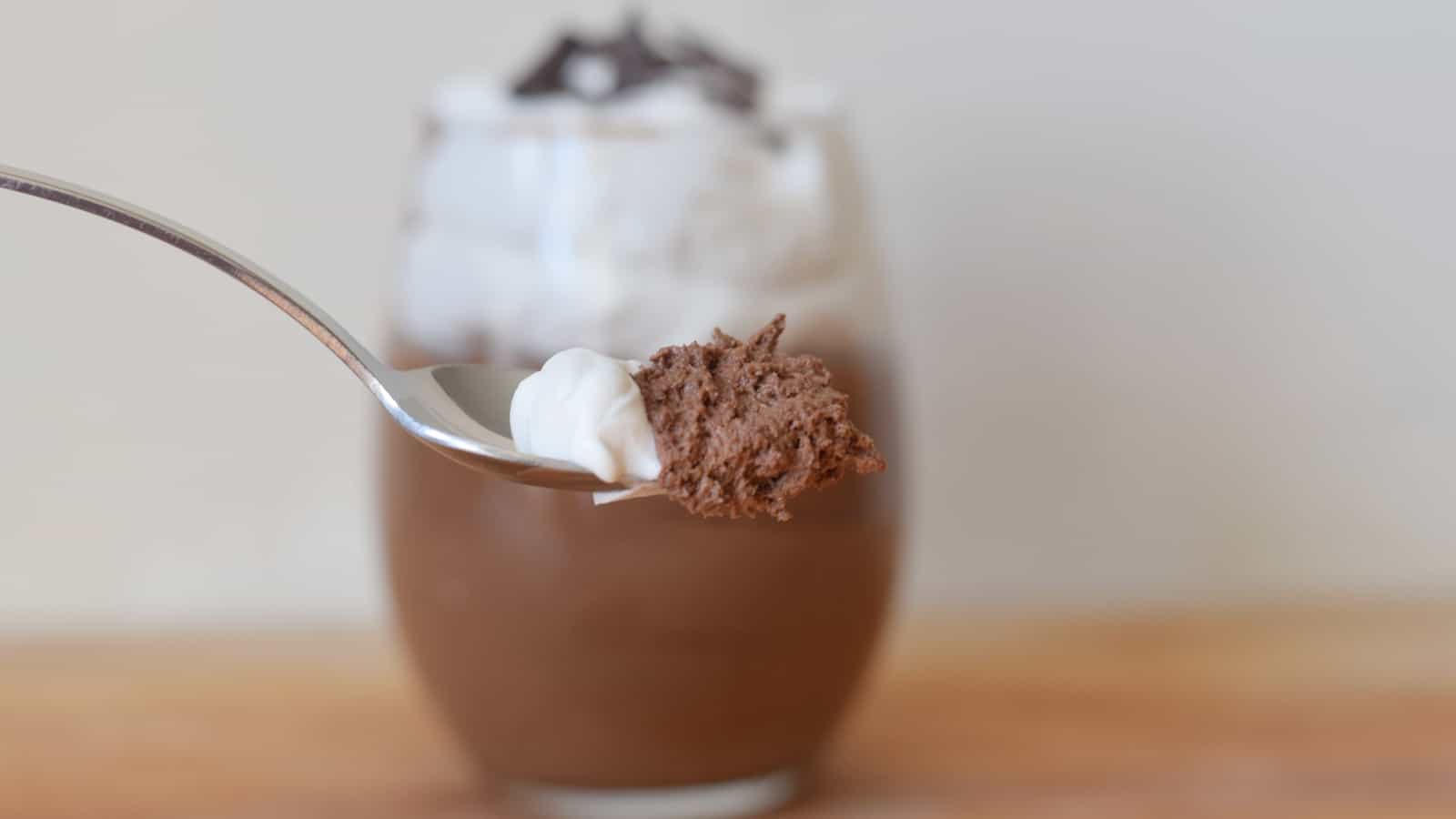 Image shows a Spoon with Baileys chocolate mousse and whipped cream and the full serving behind it.