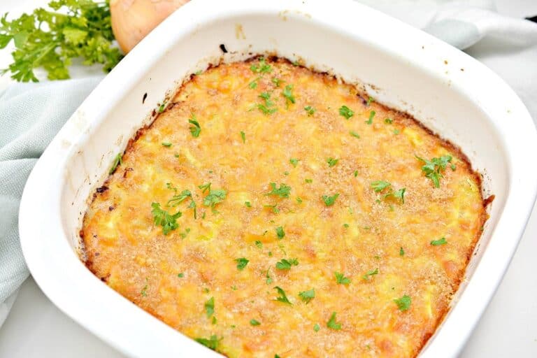 Cheesy squash casserole in a white dish.