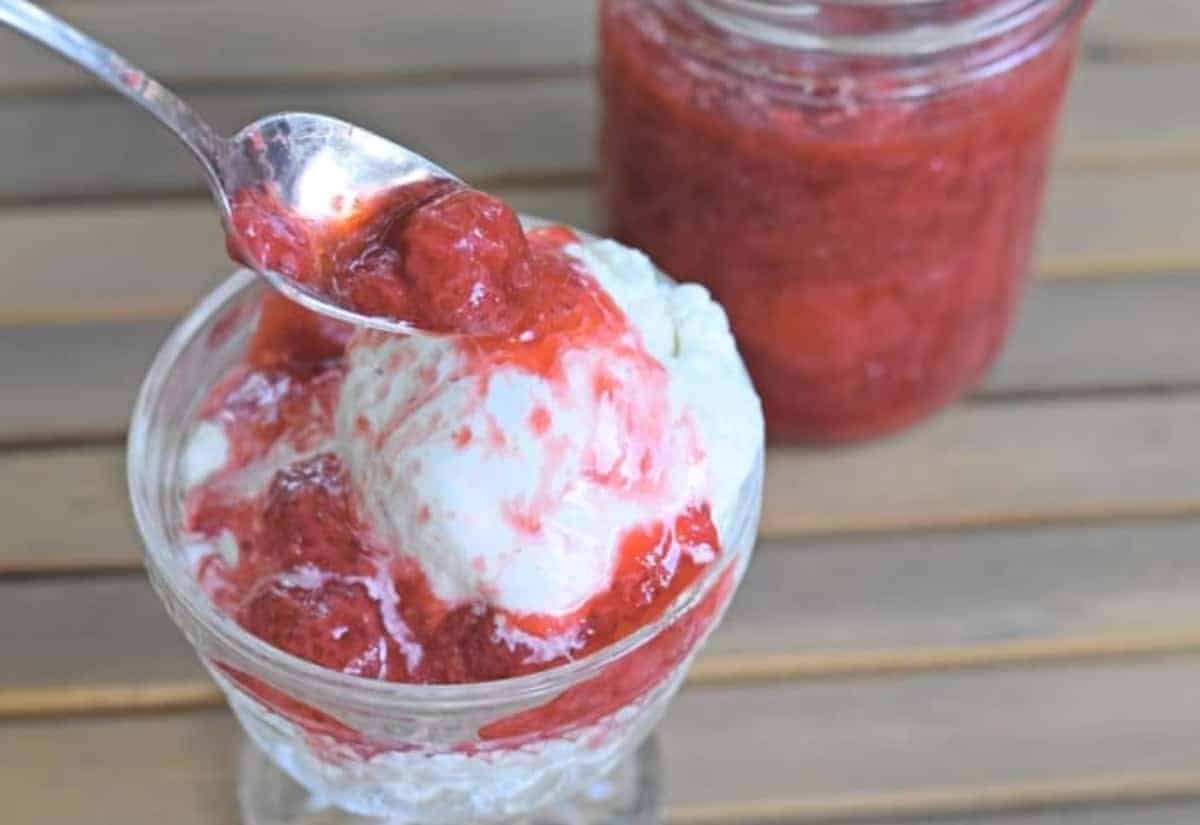 Image shows a spoon adding strawberry syrup to a bowl of ice cream.