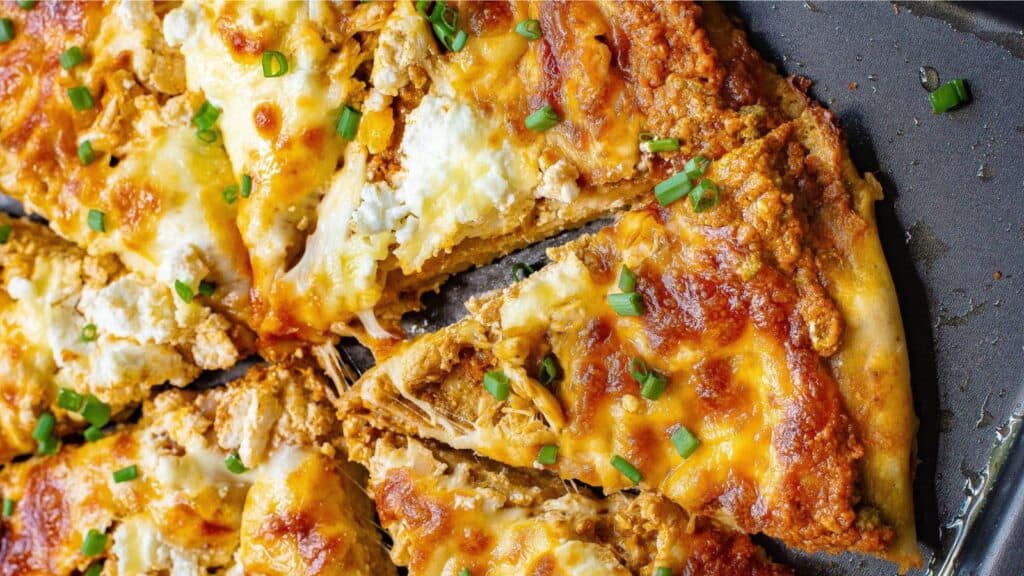 A pizza with cheese and green onions on a baking sheet.