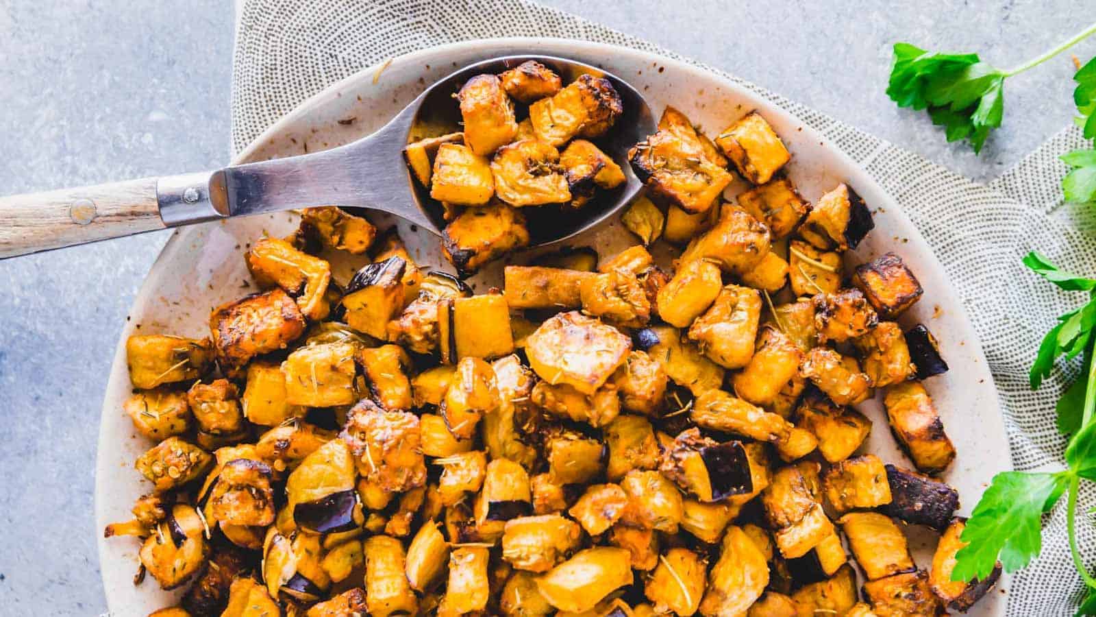 Crispy cubed eggplant roasted in the air fryer on a plate with a serving spoon.