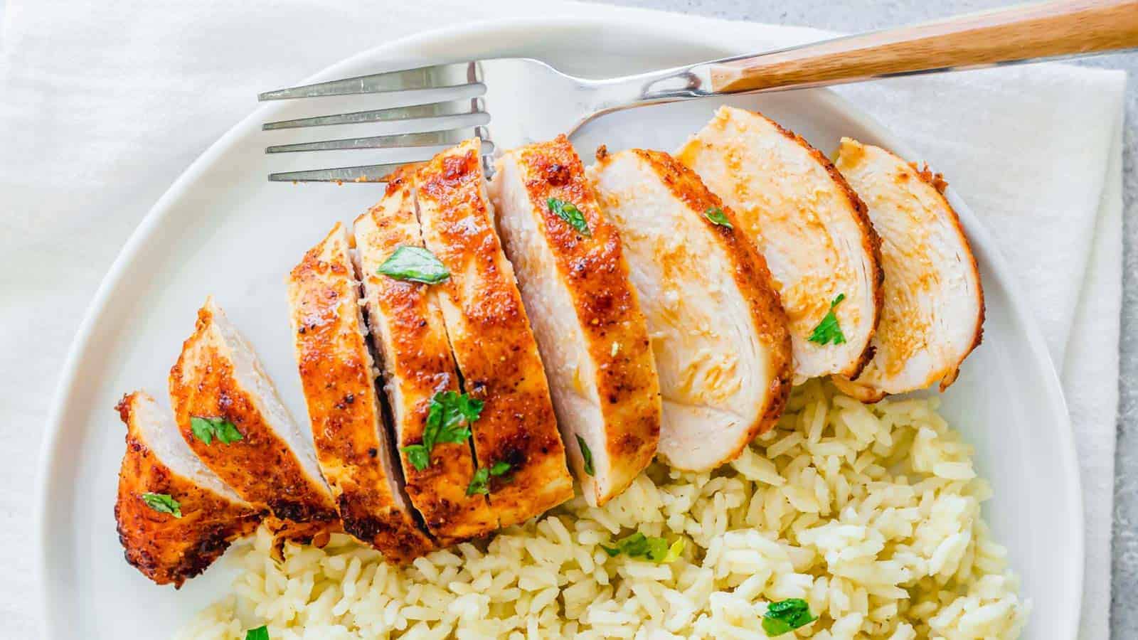 Air fryer frozen chicken breast sliced on a plate with rice and a fork.