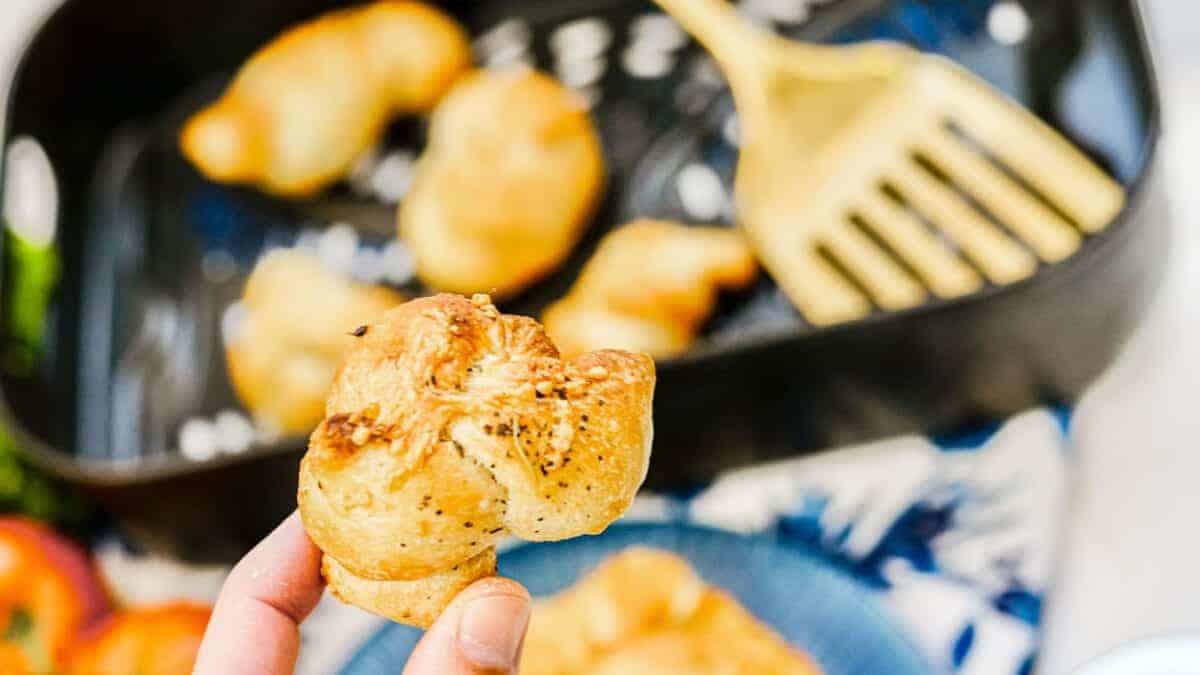 A person is holding up a garlic knot.