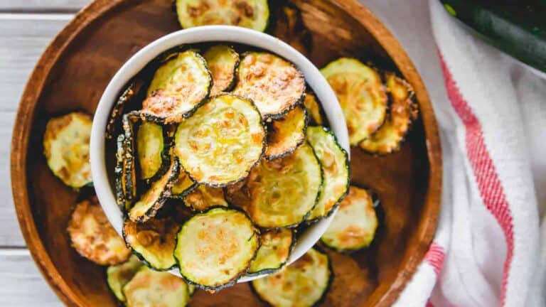 Zucchini chips in a bowl on a wooden table.