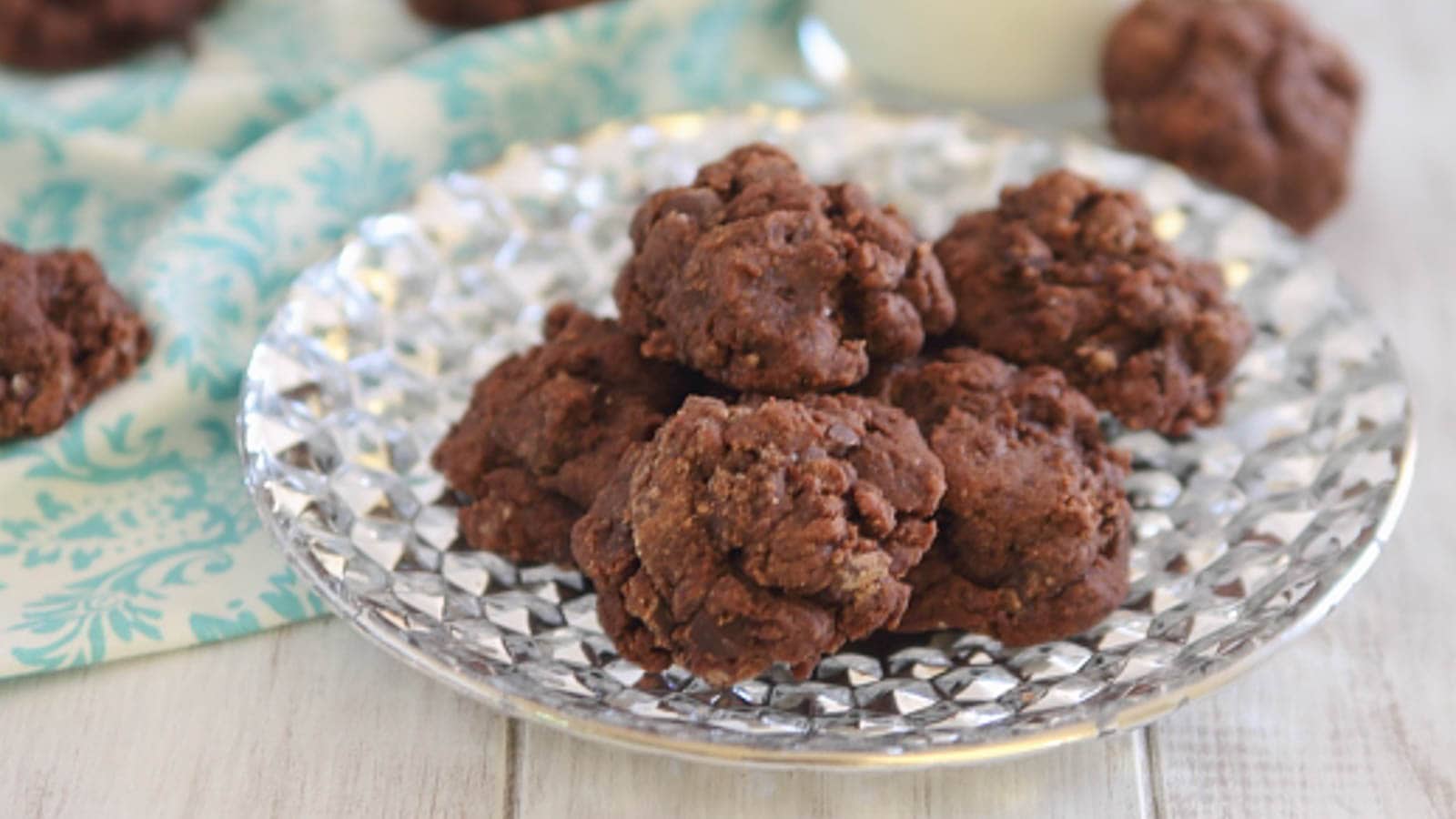 Chocolate oatmeal cookies on a silver plate with a glass of milk.