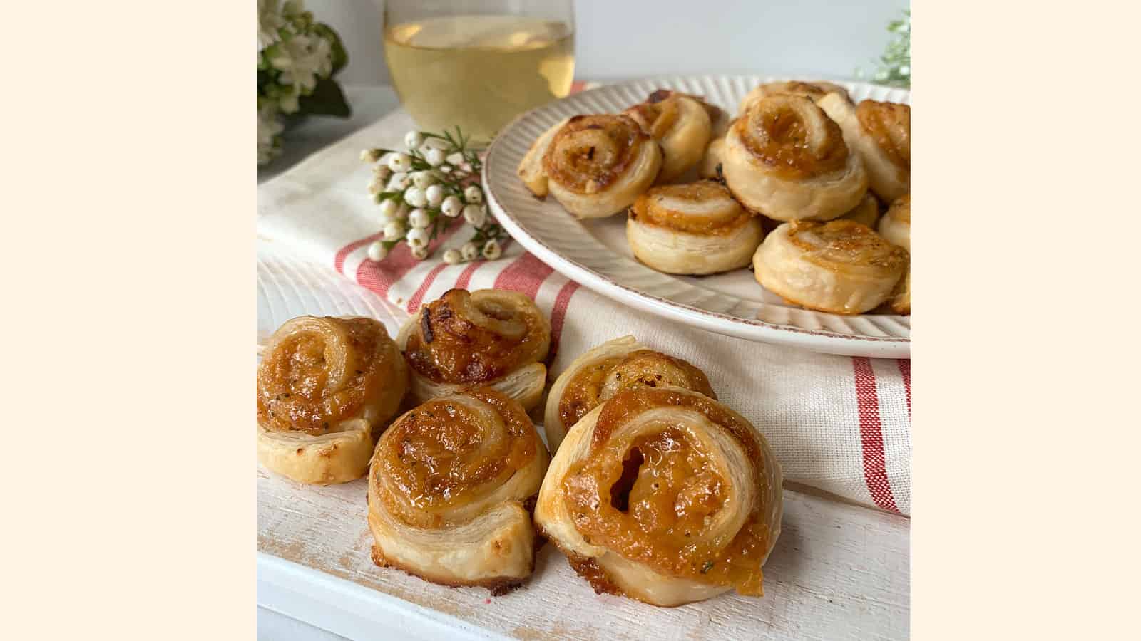 Apricot pinwheel appetizers on a white plate and on a white cutting board.