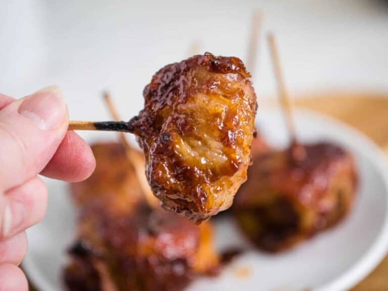 A person holding a skewer of water chestnuts on a toothpick.