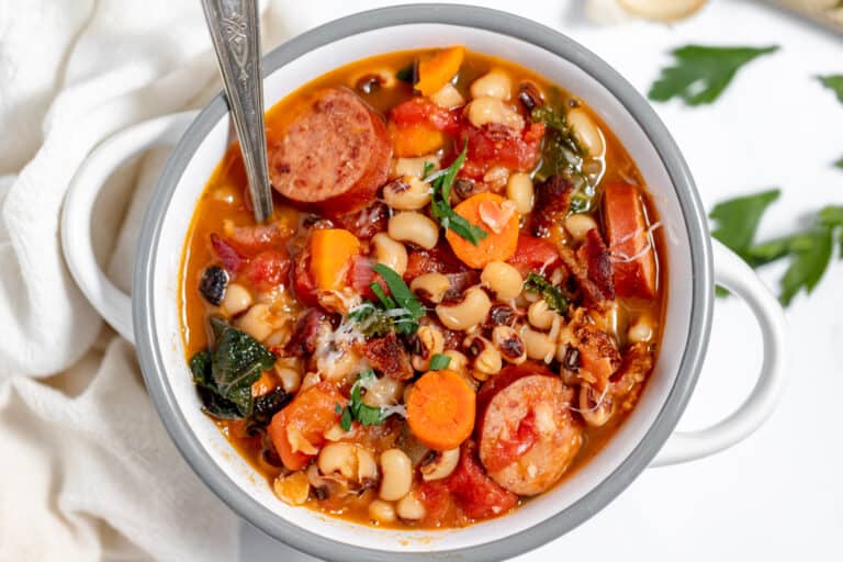 A pot of soup with sausage, beans and vegetables.