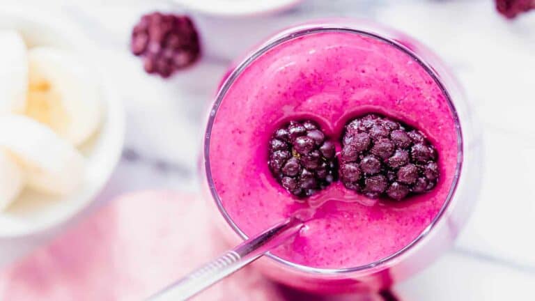 A pink smoothie with blackberries and bananas.