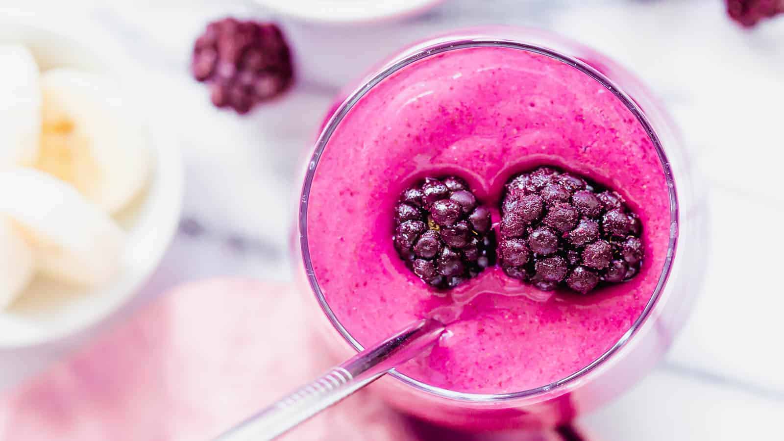 Blackberry smoothie recipe in a glass topped with frozen blackberries.