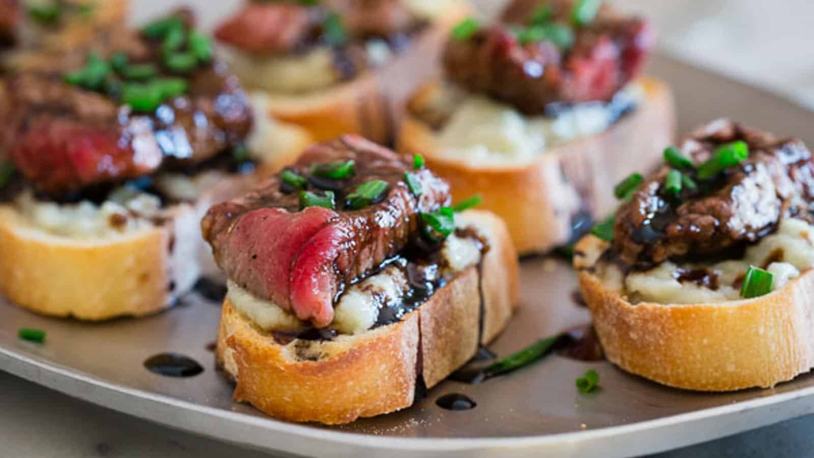 A plate of appetizers with steak and mashed potatoes.