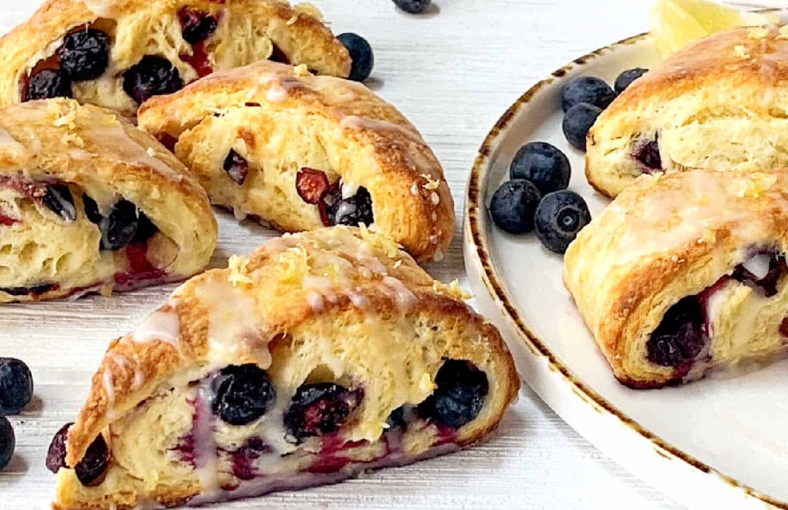 Blueberry lemon scones on a white platter with fresh blueberries.