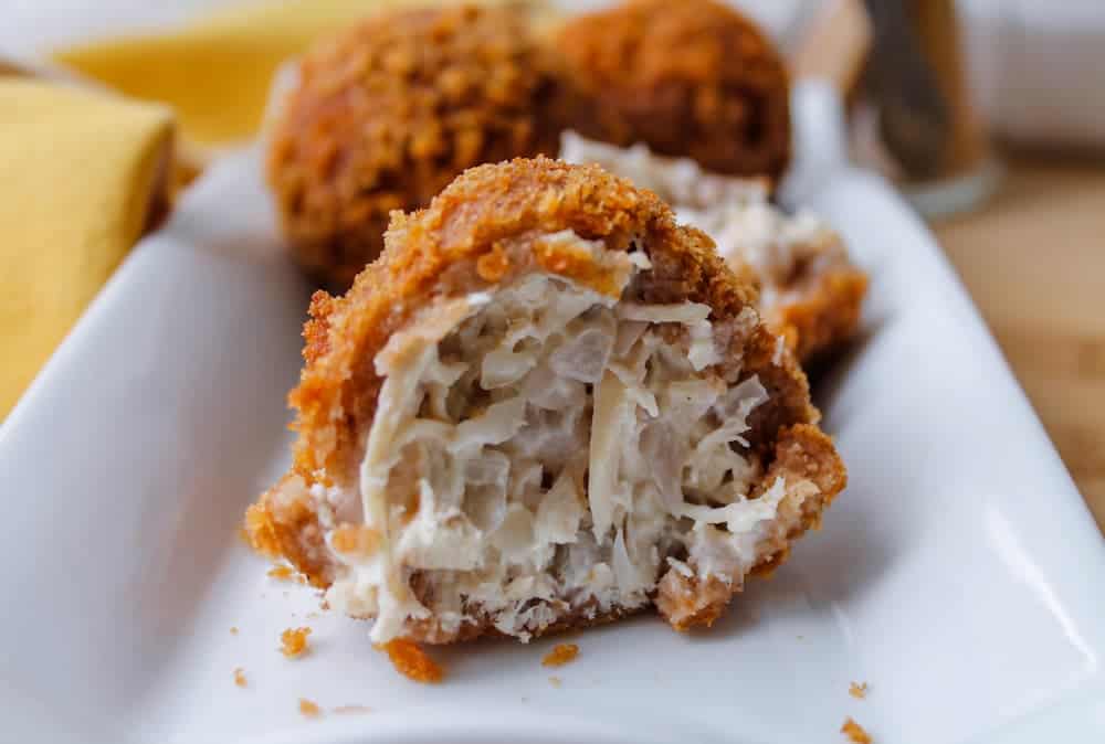 A Brazilian Coxinha on a serving plate with a bite taken out of it.