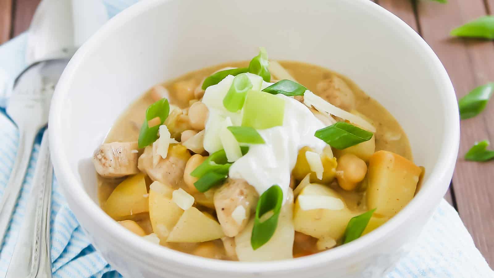 A bowl of chili with apples, beans and sour cream.