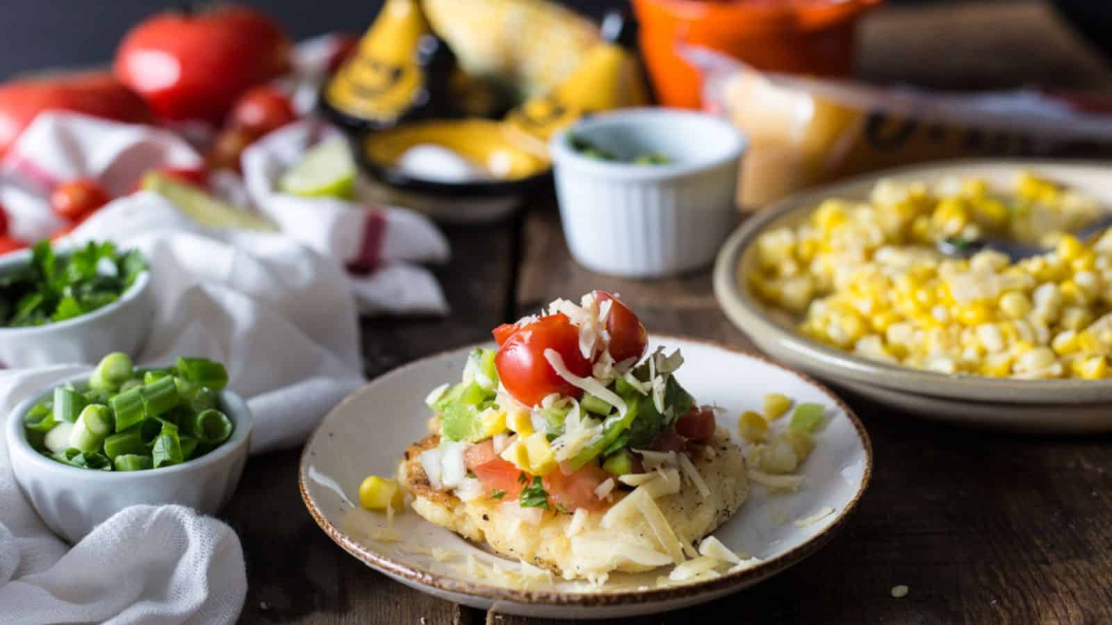 A plate with corn, tomatoes and cheese on it.